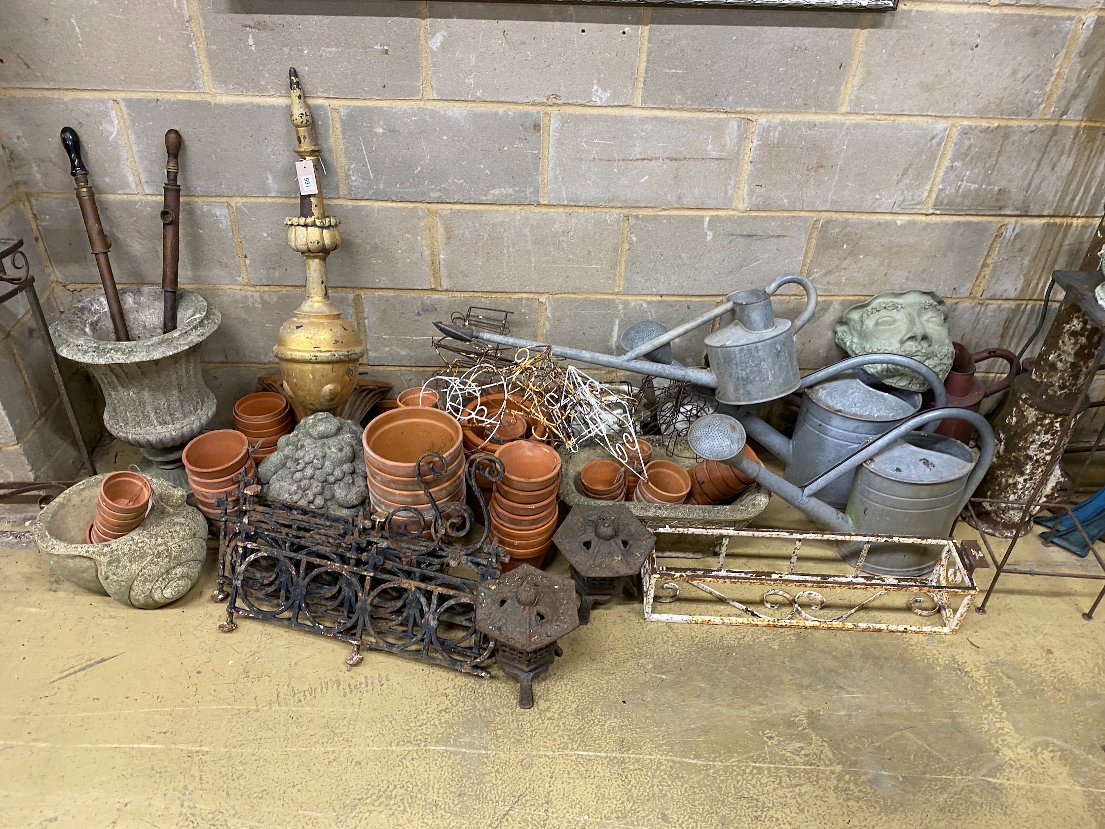 A large quantity of assorted garden ornaments, terracotta pots, galvanised watering cans, bench ends, etc.